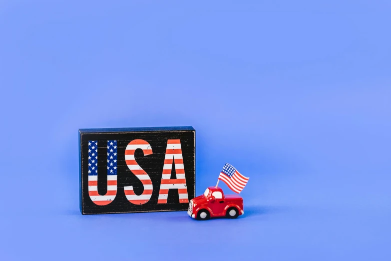 a toy truck with an american flag next to a usa sign, by Julia Pishtar, pexels contest winner, american scene painting, background image, mini model, red and blue neon, 4 k product photo