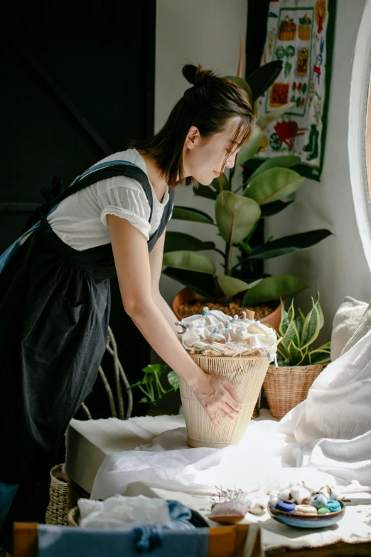 a woman putting something in a bucket on a bed, inspired by Juan Luna, pexels contest winner, bakery, houseplant, wearing maid uniform, profile image