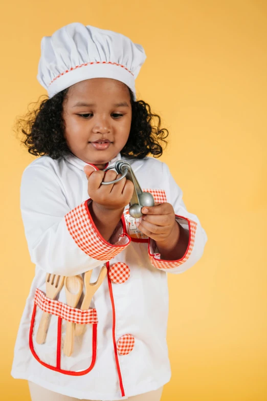 a little girl wearing a chef's hat and cooking utensils, pexels contest winner, action figure, white uniform, diverse, let's play
