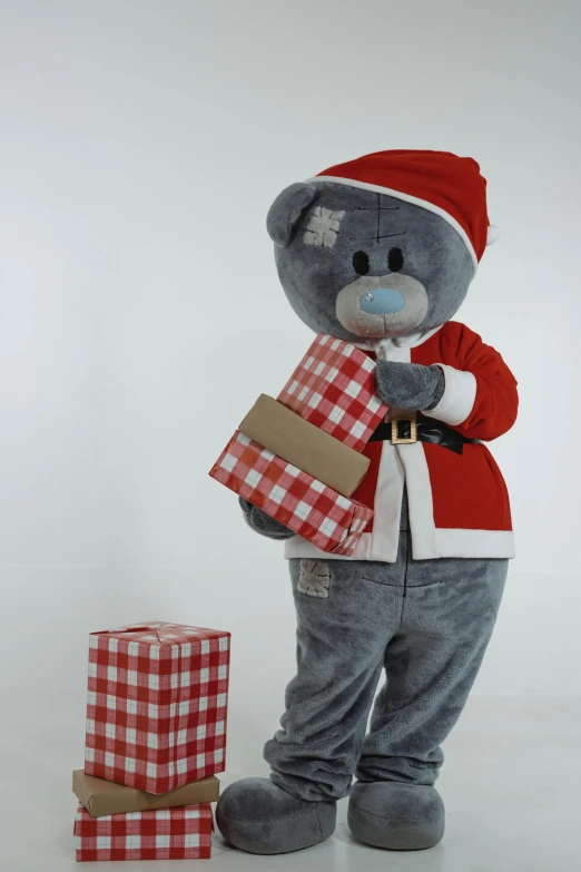 a teddy bear standing next to a pile of presents, red and blue garments, character posing, grey, box