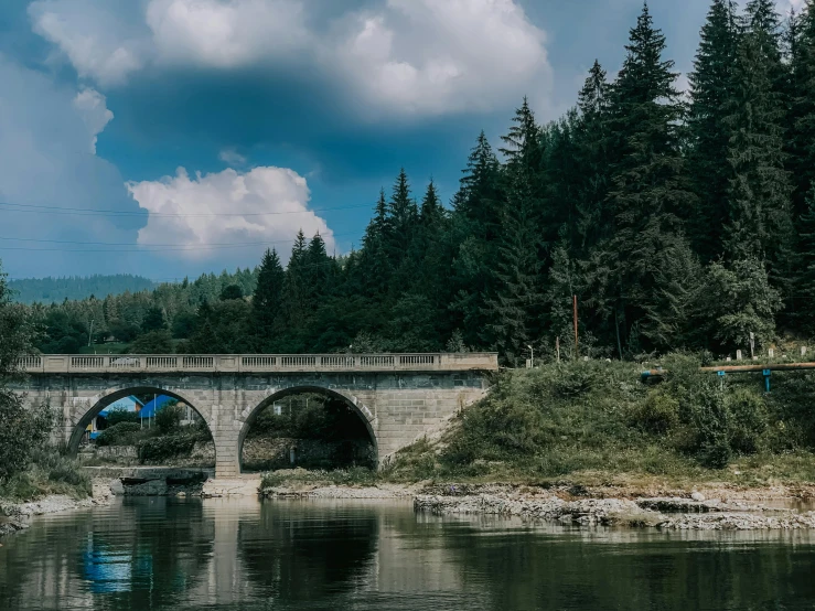 a bridge over a body of water surrounded by trees, by Adam Szentpétery, pexels contest winner, carpathian mountains, 2 5 6 x 2 5 6 pixels, white stone arches, 1940s photo