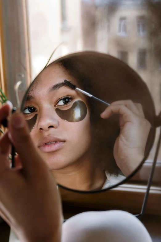 a woman getting her make up done in front of a mirror, trending on pexels, renaissance, black eye patch over left eye, natural complexion, late afternoon sun, goggles on forehead