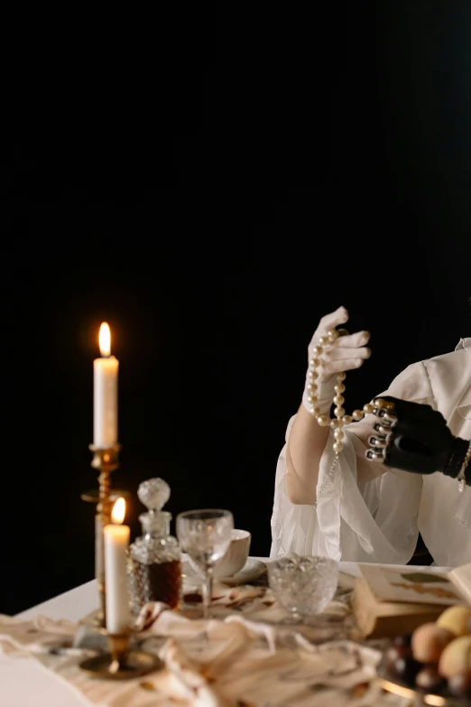 a woman sitting at a table with a plate of food, inspired by Pietro Longhi, unsplash, baroque, gloves and jewelry. motion, candlelit, 1 9 1 0 s film scene, white long gloves