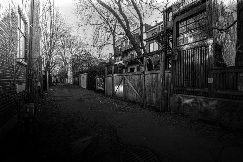 a black and white photo of an alley, by David Allan, on a sidewalk of vancouver, fence, urbex, by greg rutkowski