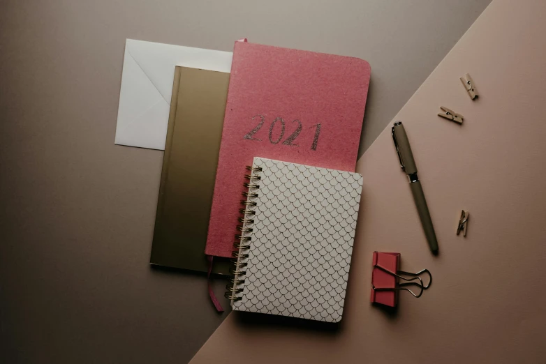 a pink notebook sitting on top of a table next to a pair of scissors, trending on pexels, red brown and grey color scheme, beige, thumbnail, various posed