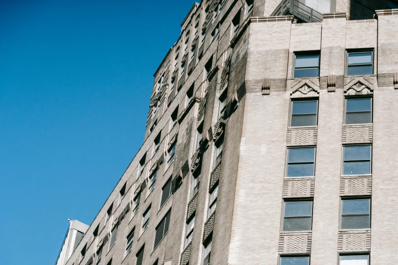 a clock mounted to the side of a tall building, a photo, unsplash, modernism, rundown new york apartment, clear blue sky, ignant, high details photo