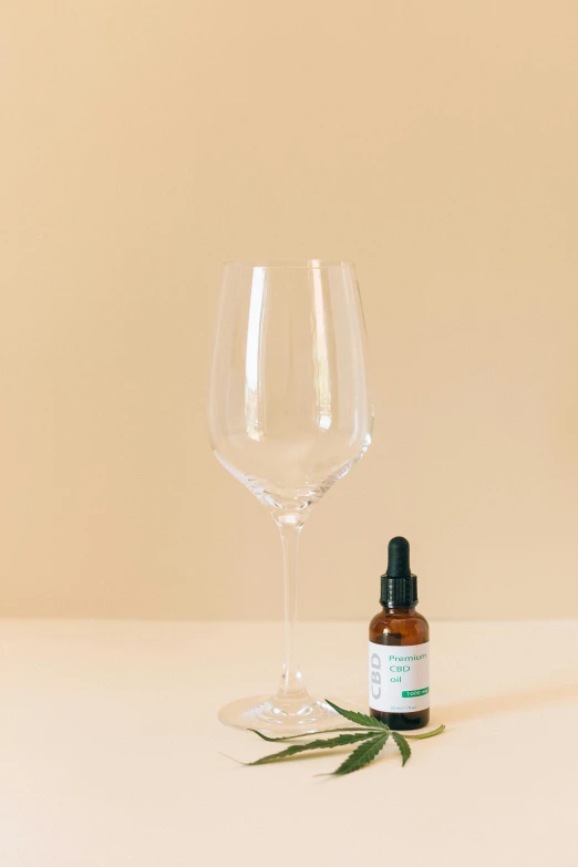 a bottle of essential oil next to a glass of wine, organic shape, slightly minimal, product view, plants in glasses