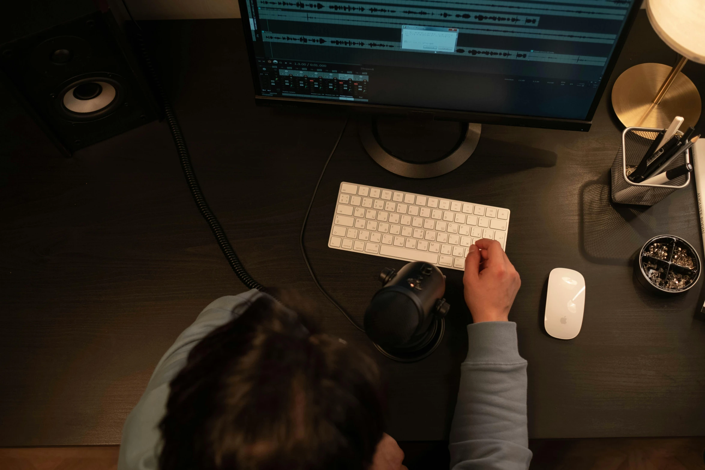 a man sitting at a desk in front of a computer, trending on pexels, video art, bottom lighting, scrolling computer mouse, sitting in front of a microphone, a high angle shot