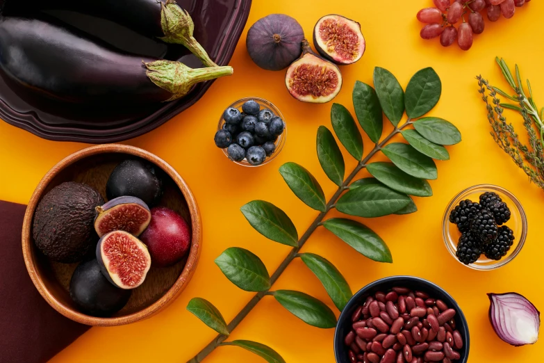 various fruits and vegetables laid out on a yellow surface, by Julia Pishtar, trending on pexels, purple foliage, magnesium, fig leaves, detailed product image