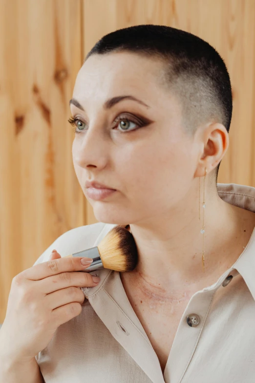 a woman brushing her hair with a brush, an album cover, inspired by Aya Goda, trending on pexels, shaved face, sofya emelenko, natural make-up, lgbtq