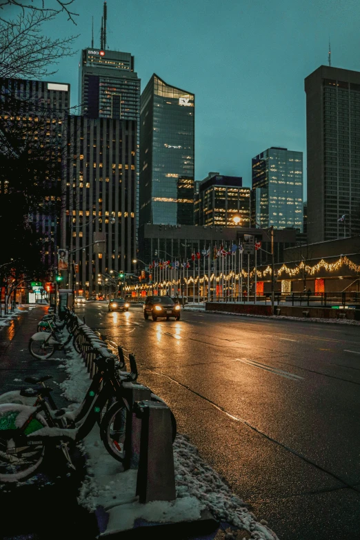 a row of bikes sitting on the side of a road, by Austin English, pexels contest winner, city night, toronto, holiday, big buildings