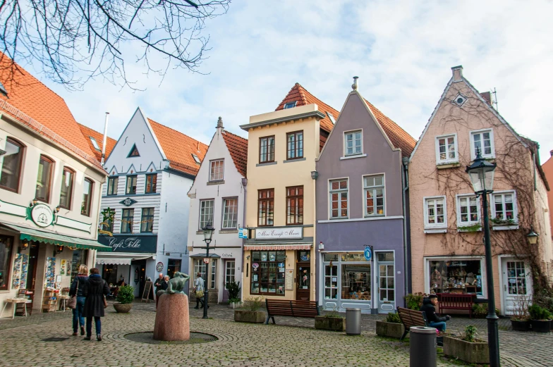 a group of people walking down a cobblestone street, by Julia Pishtar, pexels contest winner, art nouveau, lower saxony, coastal, house's and shops and buildings, square