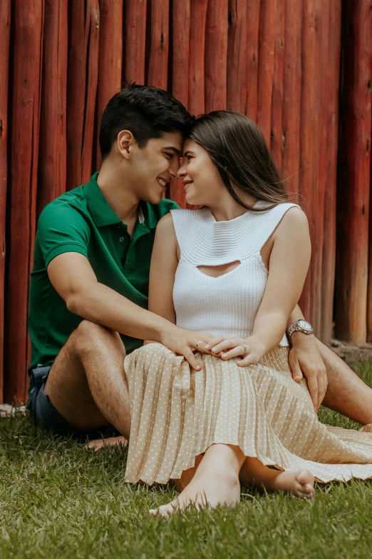 a man and woman sitting next to each other on the grass, a colorized photo, pexels contest winner, philippines, next to a red barn, cute pose, flirting expression