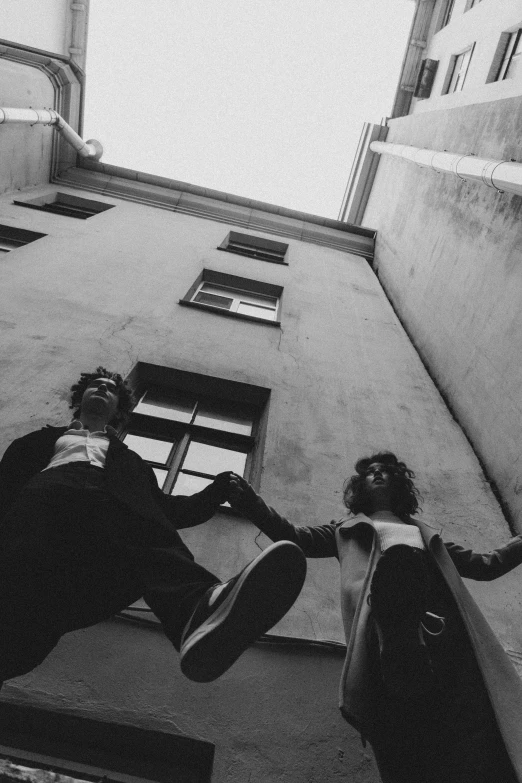 a couple of people jumping up the side of a building, a black and white photo, by Alexis Grimou, ✨🕌🌙, petros and leonid, in front of the house, roleplay