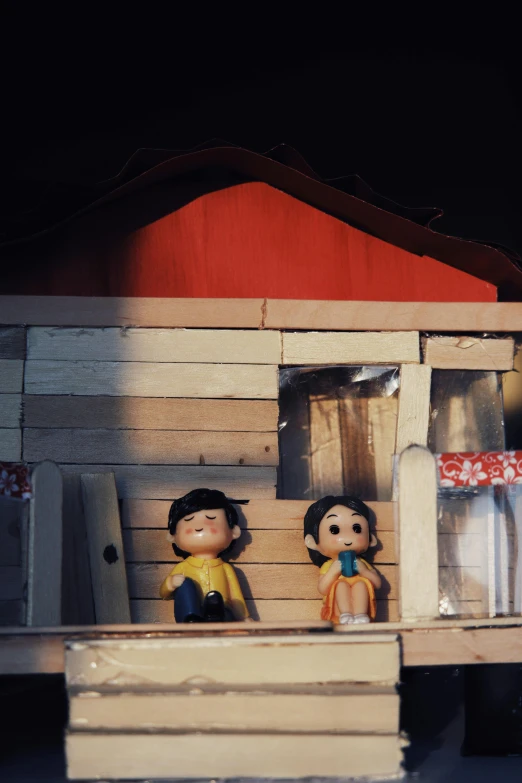 a doll house with two dolls inside of it, a cartoon, inspired by Nara Yoshitomo, unsplash, conceptual art, evening sunlight, 1970s philippines, shack close up, scene from live action movie