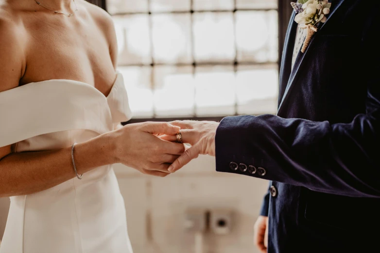 a man putting a wedding ring on a woman's finger, pexels contest winner, wearing a white tuxedo, indoor setting, lachlan bailey, in front of white back drop