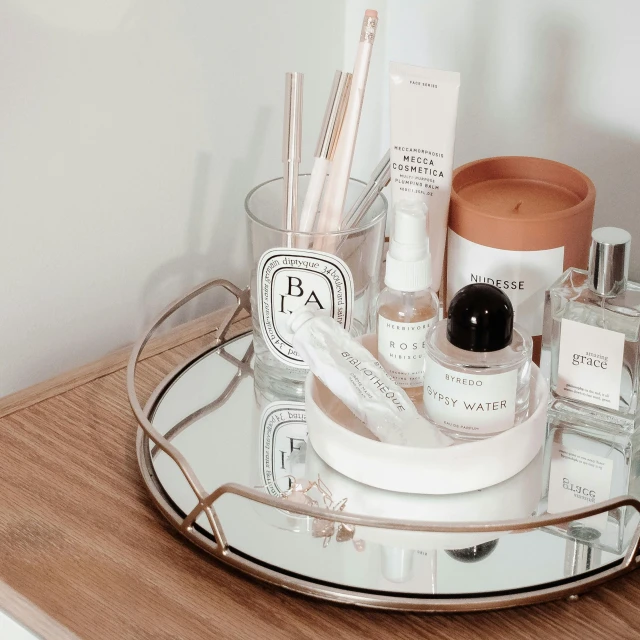 a mirror sitting on top of a wooden table, a still life, trending on pexels, vials, carrying a tray, cream and white color scheme, sephora