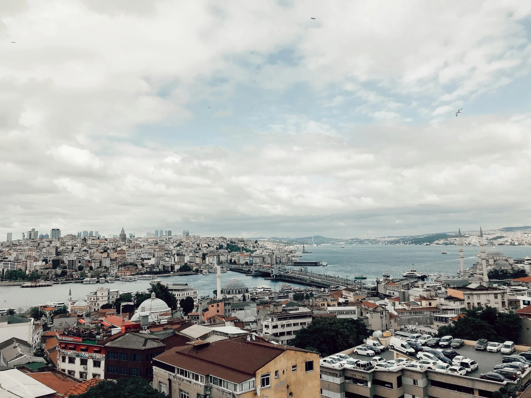 a view of a city from the top of a building, a colorized photo, pexels contest winner, hurufiyya, mixture turkish and russian, grey cloudy skies, a photo of the ocean, youtube thumbnail