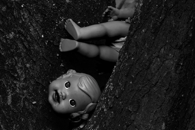 a black and white photo of a doll in a tree, unsplash, crashed in the ground, chucky, horror wallpaper aesthetic, barbie doll