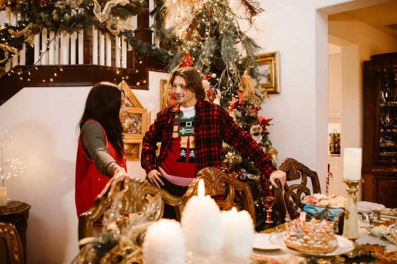 a man and woman standing in front of a christmas tree, pexels contest winner, happening, decoration around the room, ready to eat, patterned clothing, thumbnail