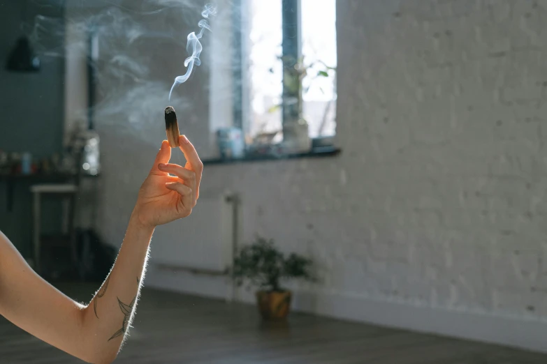 a man that is holding a cigarette in his hand, trending on pexels, light and space, picture of a loft in morning, marijuana smoke, doing witchcraft, holding a small vape