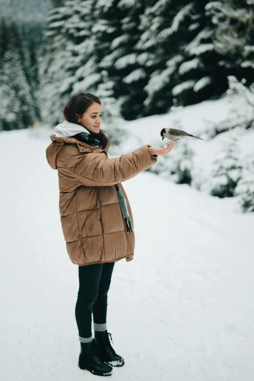 a woman standing in the snow holding a bird, pexels contest winner, dafne keen, profile image, pokimane, kids