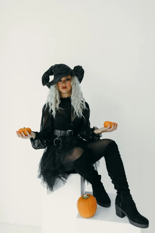 a woman in a witch costume sitting on a stool, trending on pexels, kerli koiv, nier inspired, casual black clothing, wears a destroyed hat
