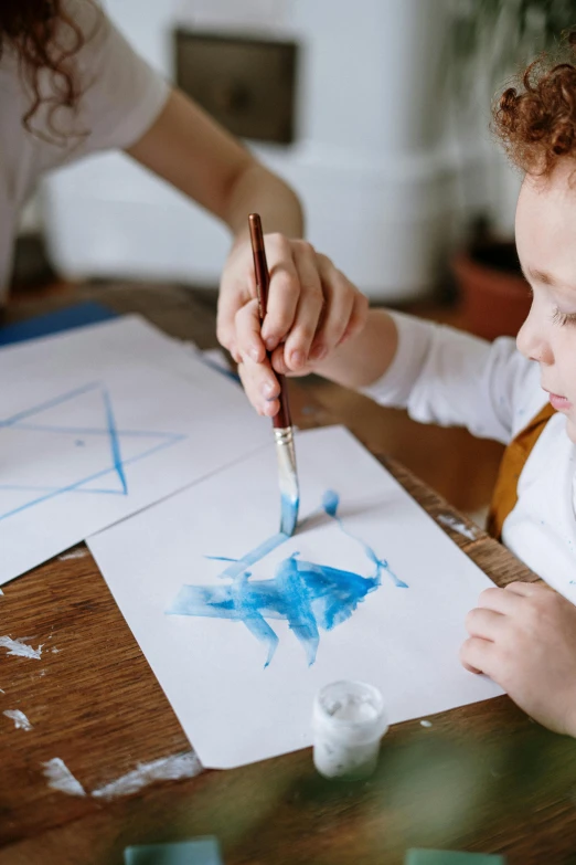 a little boy that is sitting at a table, pexels contest winner, process art, brushed white and blue paint, painting on a badge, on high-quality paper, blue print