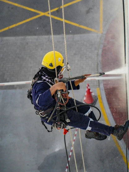 a fireman spraying water on the side of a building, by Julia Pishtar, pexels contest winner, sitting in a crane, hanging rope, low quality photo, thumbnail