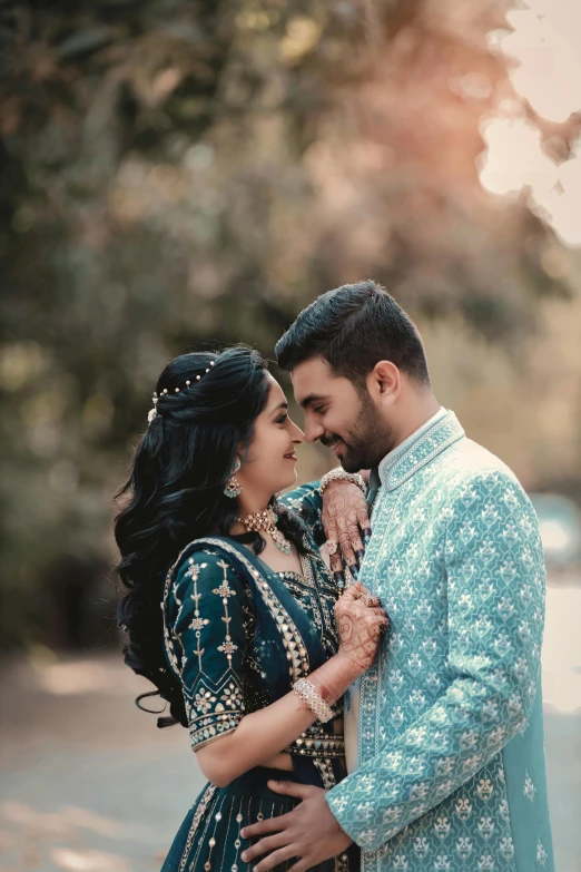 a couple standing next to each other on a road, pexels contest winner, hurufiyya, blue colored traditional wear, profile image, square, elegant smiling pose