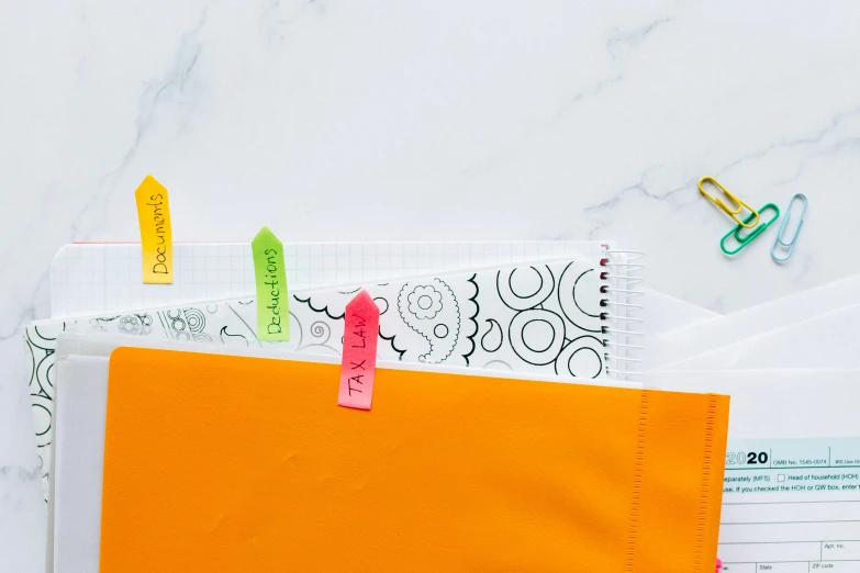 an orange folder sitting on top of a table, a silk screen, trending on pexels, poster paper with notes, zippers, colourful close up shot, white neon