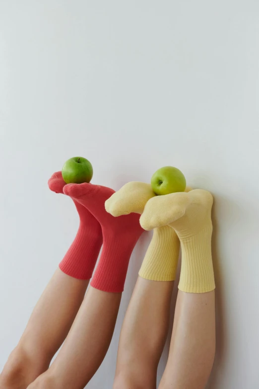 a close up of a person holding an apple, inspired by Sarah Lucas, wearing kneesocks, red+yellow colours, hands in the air, designer product