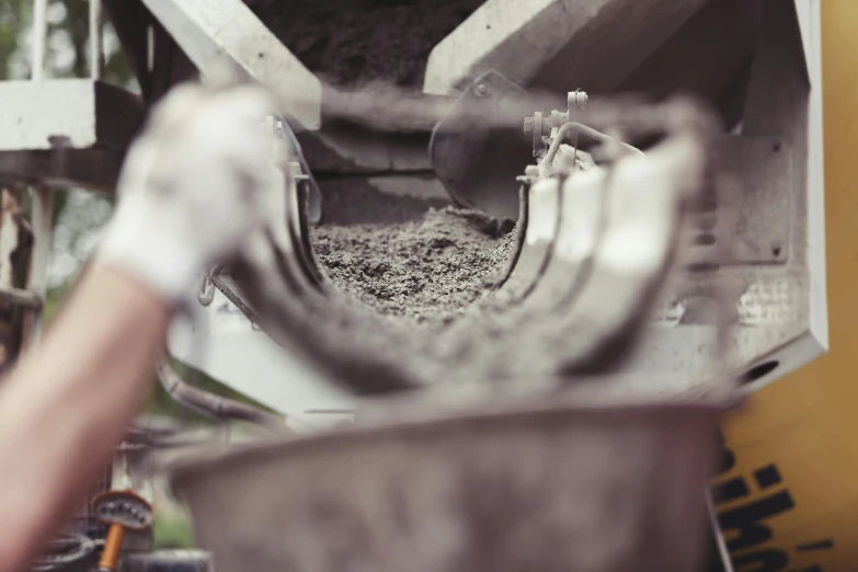 a man is pouring cement into a bucket, by Daniel Lieske, pexels contest winner, close-up product photo, grey, small manufacture, 15081959 21121991 01012000 4k