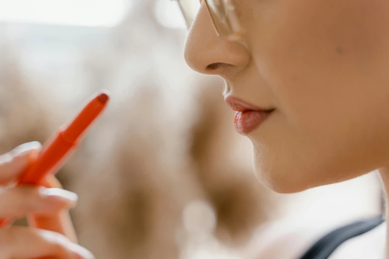 a close up of a person holding a cell phone, by Adam Marczyński, trending on pexels, photorealism, putting on lipgloss, fine details. red, complimentary eyeliner, profile image