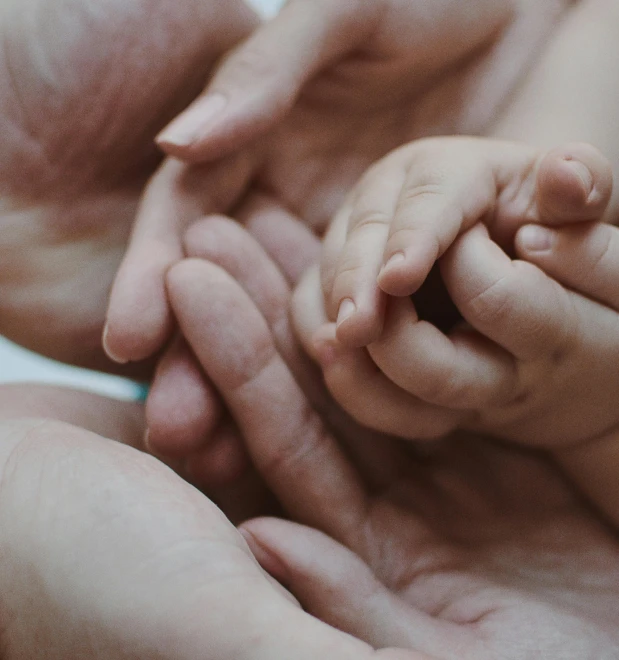 a close up of a person holding a baby's hand, pexels, incoherents, multiple limbs, cinematic still, laying down with wrists together, to protect us