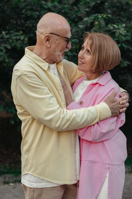a man and a woman standing next to each other, a colorized photo, pexels, cuddling, bald, two frail, romance