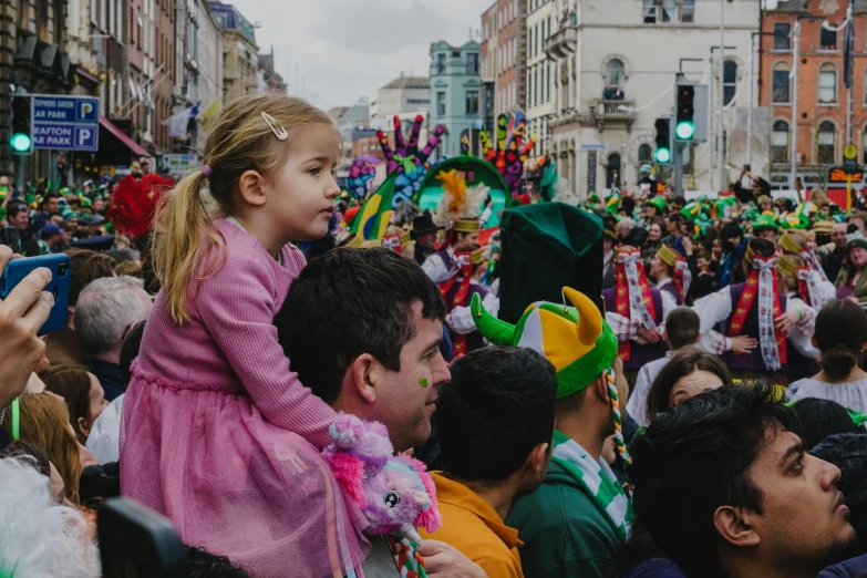 a group of people that are standing in the street, by Alice Mason, pexels contest winner, parade floats, irish, with a kid, view from the streets