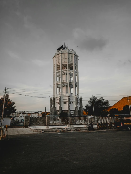 a tall tower sitting in the middle of a parking lot, by Bernardino Mei, pexels contest winner, watertank, south jakarta, preserved historical, grey