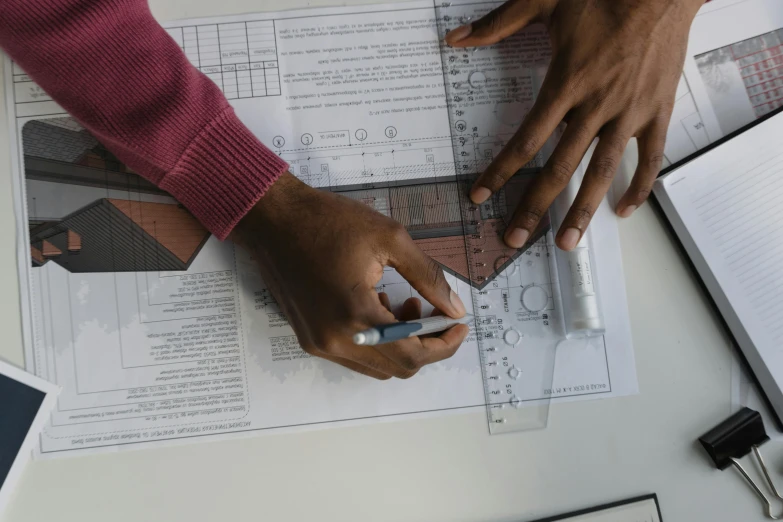 a person sitting at a table with a pen and paper, architectural scale, pointing, uploaded, thumbnail