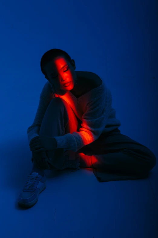 a man sitting on the ground in the dark, by Adam Marczyński, digital art, blue and red lighting, portrait willow smith, color photograph, red light