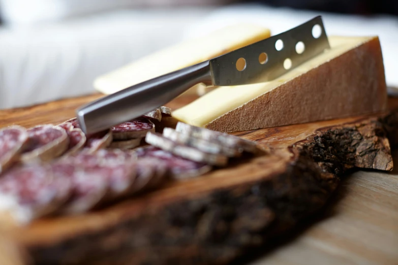 a knife sitting on top of a wooden cutting board, by Julian Allen, private press, eating a cheese platter, close up photograph, shot on sony a 7, various posed