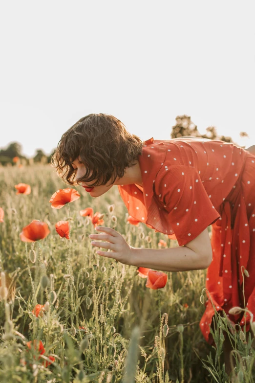 a woman in a red dress in a field of poppies, pexels contest winner, flirting, vintage aesthetic, wearing an orange jumpsuit, looking at the ground