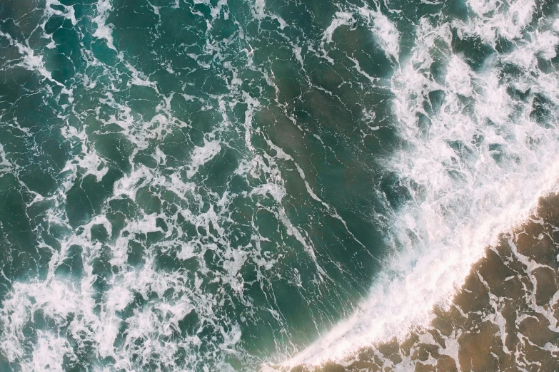 a person riding a surfboard on top of a body of water, view from the sky, zoomed out to show entire image, sea foam, unsplash 4k