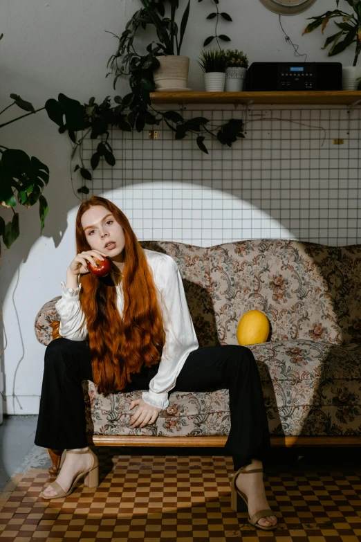 a woman sitting on a couch talking on a cell phone, an album cover, inspired by Elsa Bleda, pexels contest winner, renaissance, long ginger hair, fruit, casual pose, androgynous person