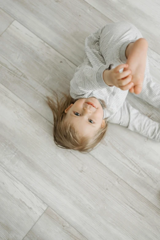 a little girl laying on the floor next to a teddy bear, pexels contest winner, hardwood floor boards, on grey background, birdseye view, 15081959 21121991 01012000 4k