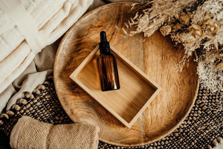 a bottle of essential oil sitting on top of a wooden tray, trending on pexels, rectangular, brown, photoshoot for skincare brand, thumbnail