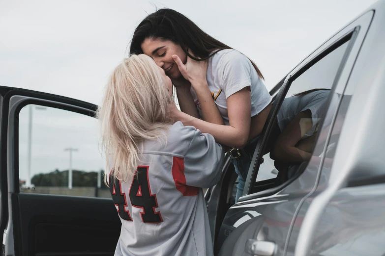 a couple of women standing next to a car, inspired by Elsa Bleda, trending on pexels, lesbian kiss, :: madison beer, red and grey only, 15081959 21121991 01012000 4k