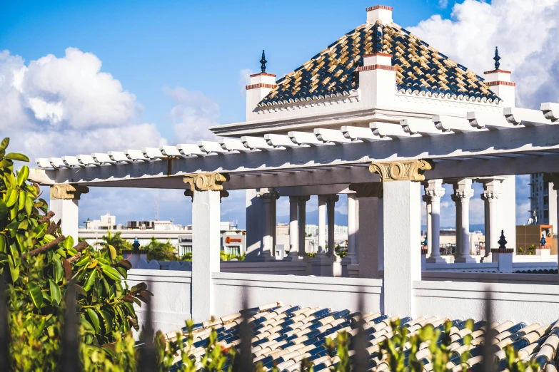 a gazebo sitting on top of a roof next to a lush green tree, a marble sculpture, by Julia Pishtar, unsplash, puerto rico, city rooftop, moroccan tile archways, blue sky