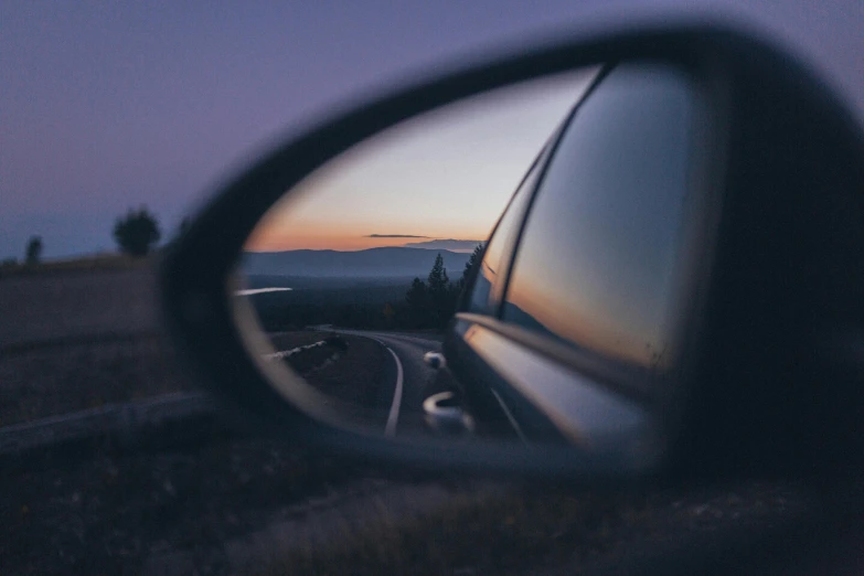a rear view mirror on the side of a car, by Adam Szentpétery, pexels contest winner, realism, dusk setting, telephoto vacation picture, half turned around, eye reflection