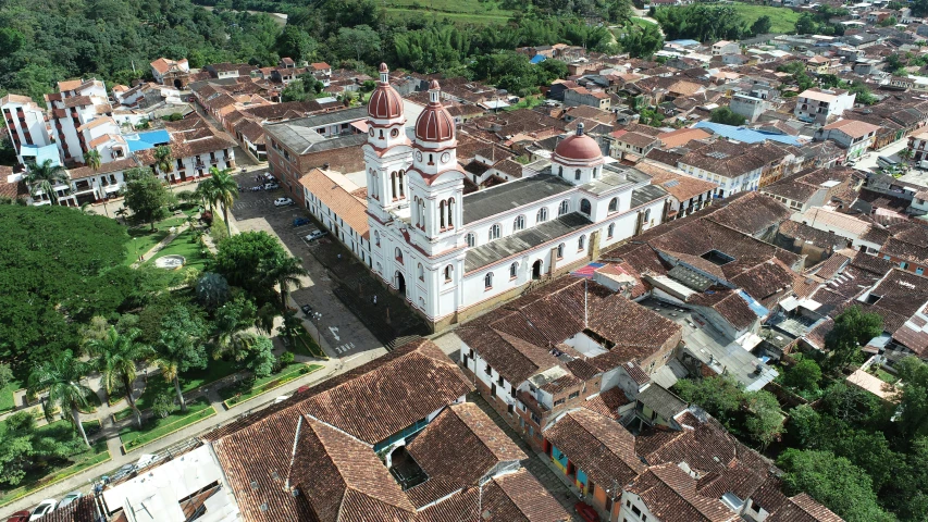 an aerial view of a town with a clock tower, a portrait, colombia, white buildings with red roofs, taken in the early 2020s, square